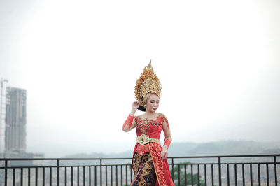 Portrait of woman with custom indonesia traditional wedding standing against railing