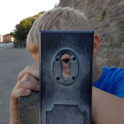 Boy looking through old keyhole against road