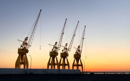 Cranes against sky during sunset