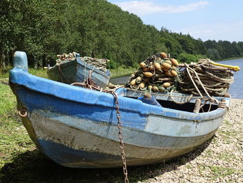 Fishing boat moored on shore against sky