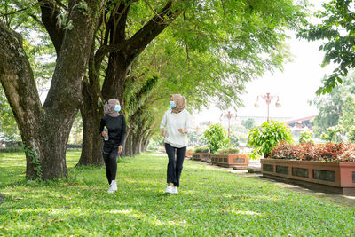 Full length of friends standing on grass against trees