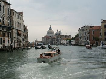 Boats moving on grand canal amidst buildings against sky