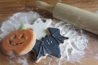 Halloween cookies, flour and rolling pin on wooden table