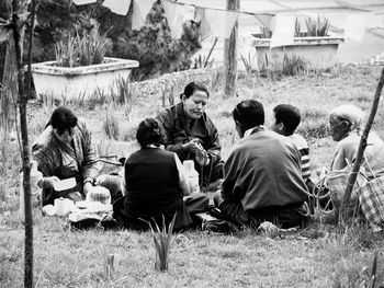 Rear view of people relaxing on field