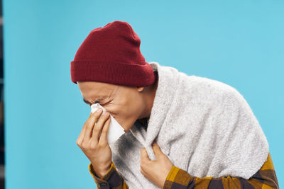 Close-up of man sneezing against colored background