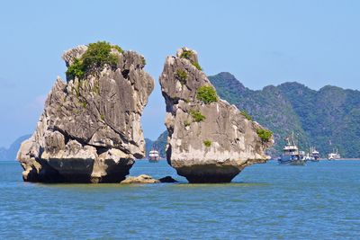 Rock formations in sea against clear blue sky