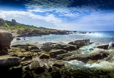 Scenic view of rocky beach against cloudy sky
