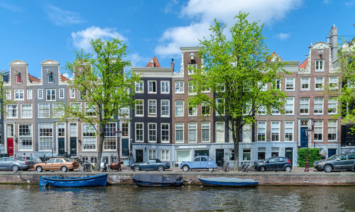 Boats moored in canal by buildings against sky