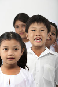 Portrait of friends singing while standing against white background