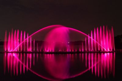 Illuminated fountain against sky at night