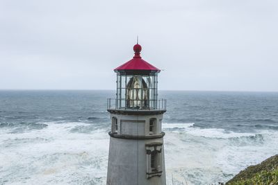 Lighthouse by sea against sky