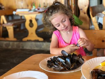 Girl holding seashell by table at restaurant