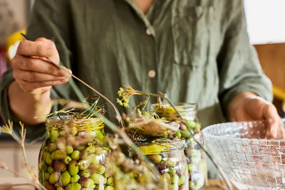 Woman prepares fermented olives in glass jars in the kitchen. autumn vegetables canning. 
