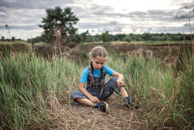 Full length of girl sitting on field