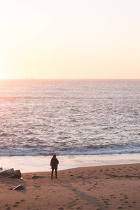 Man standing on beach against sky during sunset