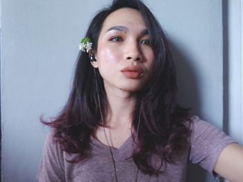 Portrait of smiling young woman standing against wall