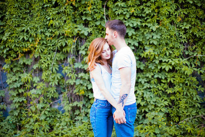 Young couple standing against plants