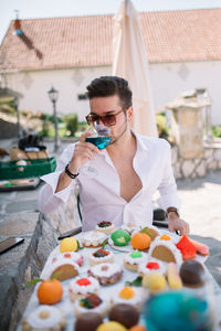 Handsome man sitting outdoors and drinking blue wine.