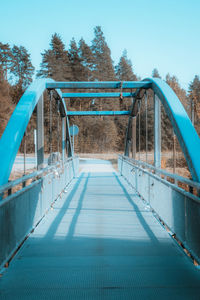 Footbridge over swimming pool against clear blue sky