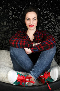 Portrait of smiling young woman sitting on rug at home 