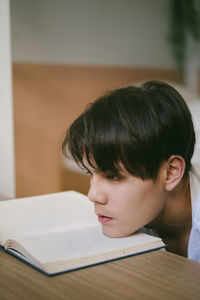 Portrait of boy with open book on table