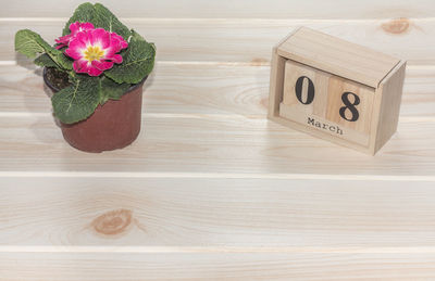 Wooden march 8 calendar, next to flower pots on wooden table. selective focus. happy womans day