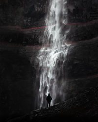 Silhouette man looking at waterfall on mountain