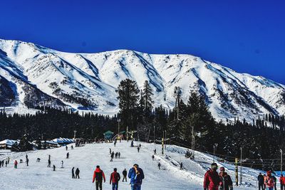 Group of people on snowcapped mountain against sky