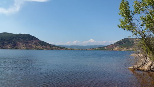 Scenic view of sea by mountains against sky