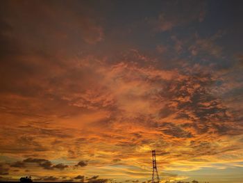 Low angle view of silhouette communications tower against sky during sunset