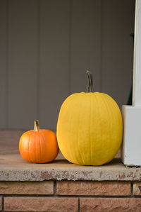 Orange pumpkins on table against wall during autumn