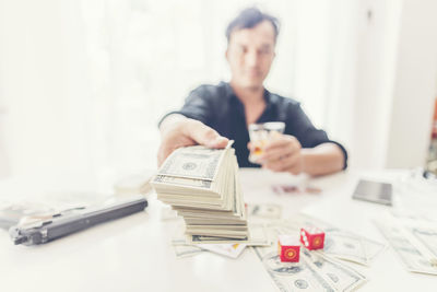 Portrait of businessman giving money while gambling at desk in office