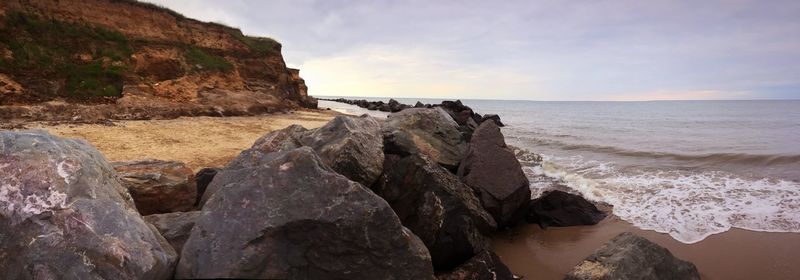 Rock formations by sea against sky