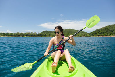 Woman paddling kayak in the sea again blue sky