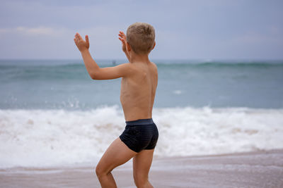 Full length of shirtless man standing at beach