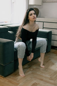 Young woman sitting on sofa at home