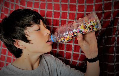 Close-up of boy eating from bottle at home