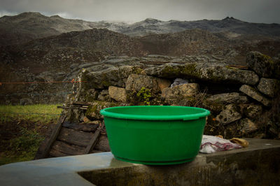 Green bucket on railing against mountains