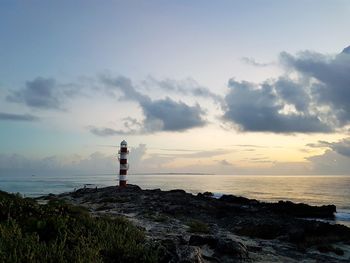 Lighthouse by sea against sky