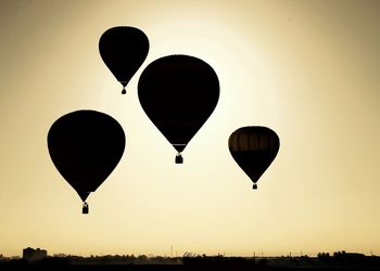 Silhouette hot air balloons against clear sky during sunset
