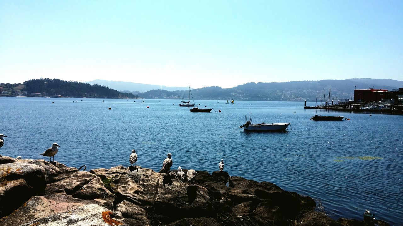 clear sky, water, copy space, nautical vessel, transportation, boat, mountain, mode of transport, blue, scenics, tranquility, tranquil scene, sea, beauty in nature, nature, moored, lake, sunlight, river, outdoors