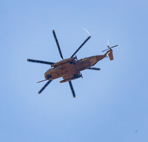 Low angle view of helicopter flying against clear blue sky