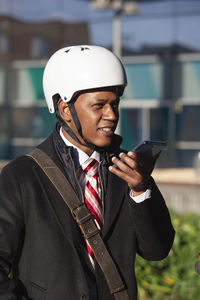Businessman in a scooter helmet holds the phone and talks on voice messaging person