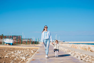 Woman with umbrella on shore against clear sky