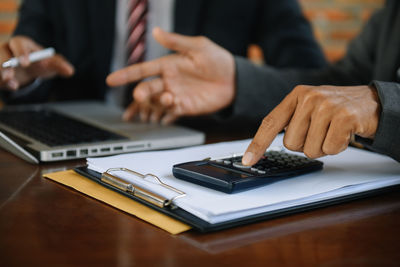 Midsection of businessman using laptop on table