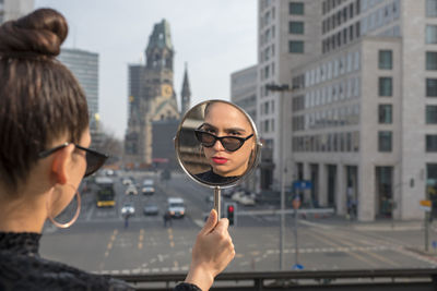 Portrait of woman holding mirror in city