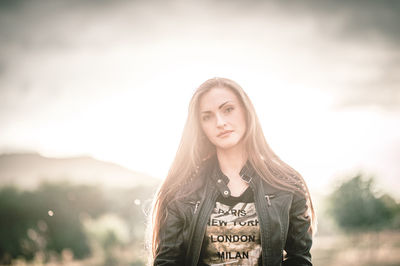 Portrait of young woman standing against sky