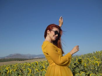 Portrait of young woman standing against clear blue sky