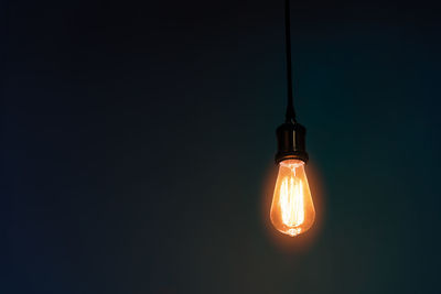 Close-up of illuminated light bulb against black background