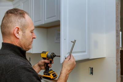 Man drilling cabinet at home